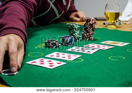 Poker chips with cards on a green table, bets placed and cards dealt