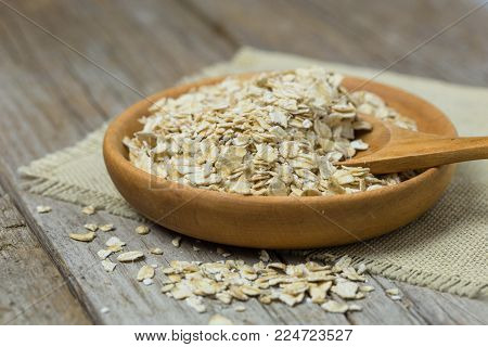 Oat Flakes Or Oatmeal In Wooden Bowl On Rustic Wood Table. Rolled Oat Is Clean Food For Health Lover
