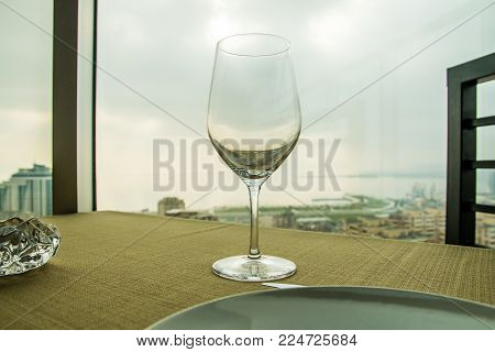 Empty wine glass on the table in front of a window. Close up shot.