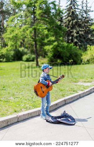 KYIV, UKRAINE May 01, 2016. Boy playing on acoustic guitar outdoors. Little street musician