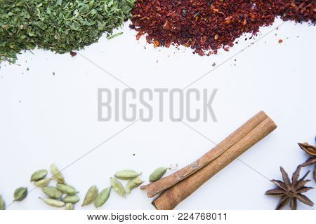 Dry herbs, crushed red pepper, cinnamon sticks, beans and clovess isolated on white background with copy space
