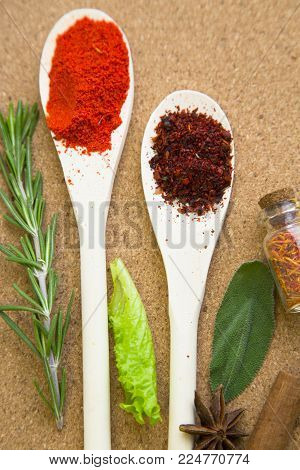 Cooking hot spicy meal. A set of spices in wooden spoons and glass jar, fresh herbs, cloves and cinnamon sticks, corkwood background with copy space, top view