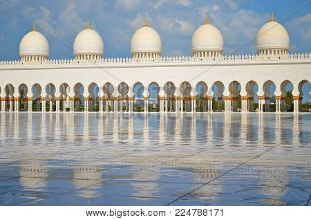 White pillars and their reflection on marble floor in Sheik Zayed Grand Mosque in Abu Dhabi in United Arab Emirates.