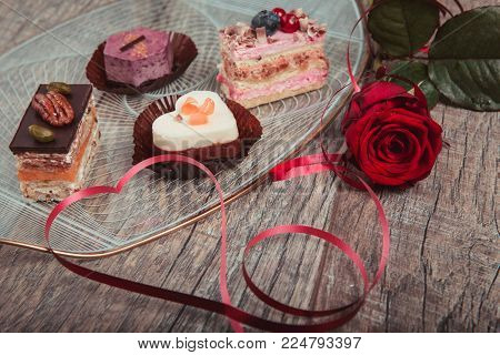 Delicious mini cupcake heart shape for Valentine Day and red ribbon on plate, red rose. Valentines day background, table place setting. Mother's, Women's, Wedding Day concept.