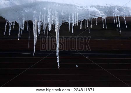 Wooden Cabin Roof Icicles In Winter. Icicles Signify Insufficient Building Insulation And Thermal Lo