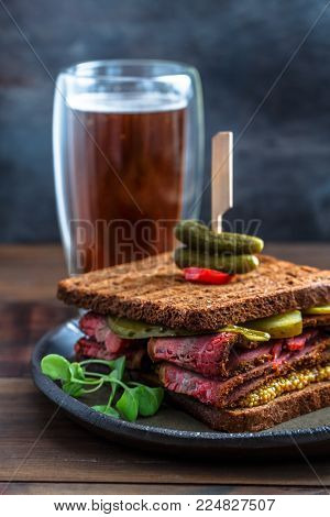 Delicious huge pastrami sandwich with beer and pickle, close view