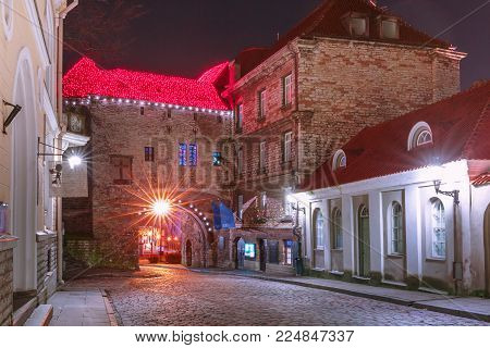 Pikk Street and Great Coastal Gate illuminated of Medieval Old Town at night, Tallinn, Estonia