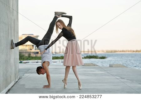 A slender ballerina dances with a modern dancer. Date of lovers. Passion and romance of dance. Modern and classical dance. Performance