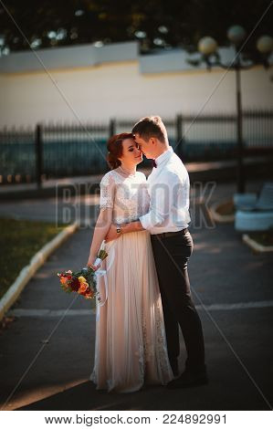 groom and the bride against the trees of the park.