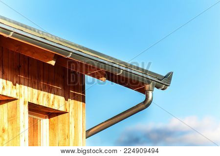 Rain gutter on the roof ecological house. Zinc gutter on the woodwork