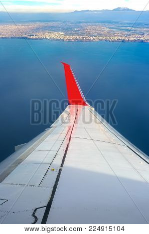 Airplane wing white in color. The plane flies over the city by the sea, Antalya.