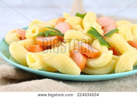 Pasta Cavatappi or Cellentani with sausages on a gray table