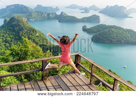 Woman tourist jumping with happy it has reached the peak mountain to see the beautiful natural landscape of sea from view point of Ko Wua Ta Lap island in Mu Ko Ang Thong, Surat Thani, Thailand
