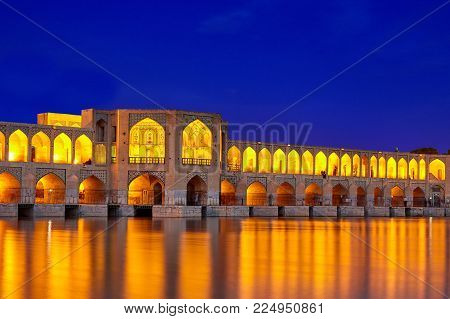 Isfahan, Iran - April 24, 2017: Night illumination of the arched stone Khaju bridge, crossing the Zayandeh river.