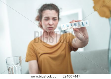 Curly Red-haired Woman Wearing Orange Shirt Holding Pills