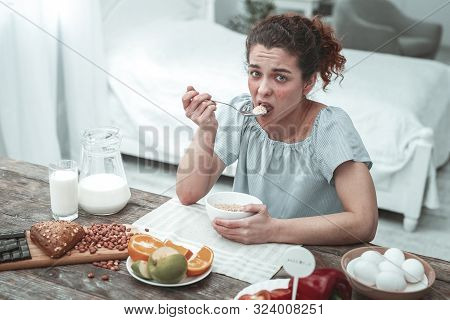 Curly Woman Not Adding Peanuts To Her Oatmeal In The Morning