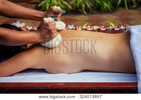 Portrait Of Young Beautiful Woman Lying On A Wooden Table In Spa Environment Flowers And Candles