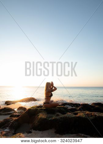 Yoga Concept. Silhouette Of Woman Practicing Yoga, Pranayama On The Beach. Young Woman Sitting On Th