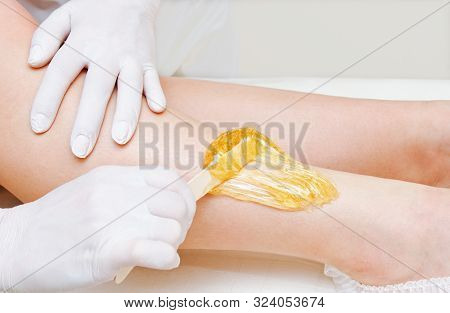 Cosmetologist Beautician Waxing Female Legs In The Spa Center Beauty Salon Closeup. Cosmetology Conc