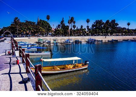 Colorful Boats On A Pier With Palm Trees In Lake Chapala Mexico On A Wonderful Sunny Day With A Blue