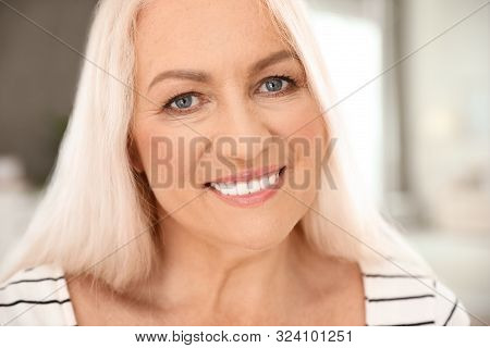 Portrait Of Mature Woman With Beautiful Face On Blurred Background, Closeup View