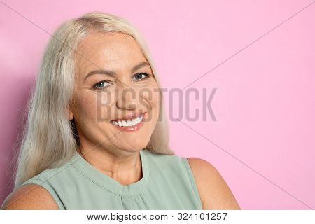 Portrait Of Mature Woman With Beautiful Face On Pink Background. Space For Text