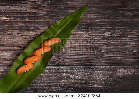Sushi Set Of Salmon Nigiri On Leaf On Wooden Background. Top View With Copy Space