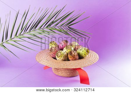 Opuntia Fruit In A Straw Hat With A Palm Leaf On A Trendy Purple Background. Prickly Pear Or Fichi D