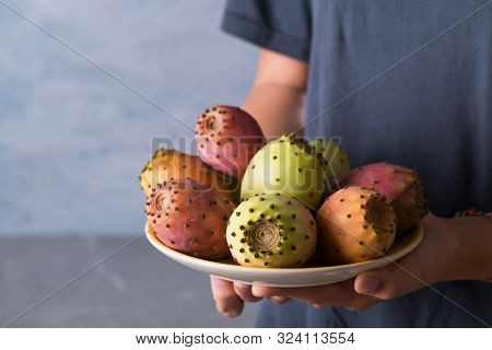Female Hands Hold A Plate With Ripe Fresh Fruits Of Prickly Pear On A Gray Background, Selective Foc