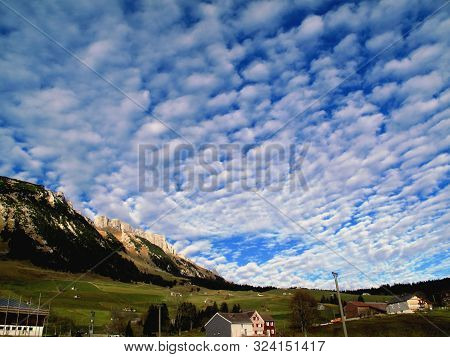 A Dramatic Cloudy Sky Over The Village Of Wildhaus In Toggenburg. Houses, Farms, Meadows, Forests, M