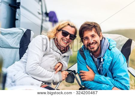 Young Couple Smiling With  Motorhome, Rv Or Campervan On Beach.