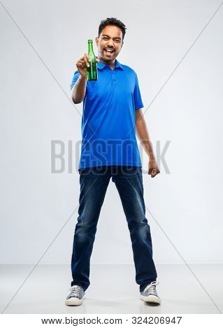 emotion, expression and success concept - happy indian man or sports fan beer bottle celebrating victory over grey background