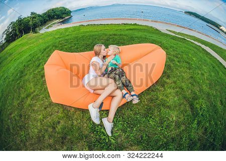 Mother And Son Resting On An Air Sofa In The Park.