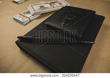 A Black Notebook , A Pen And Dollar Cash Banknotes On Wooden Background - Concept Of Financial Manag