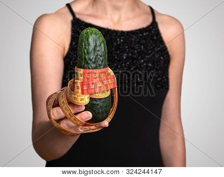Woman Holding Cucamber With Tape Masure. Diet Or Sexual Issues Concept