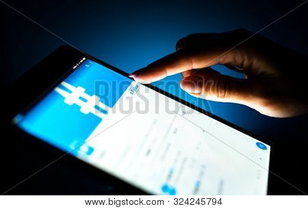 Kharkiv, Ukraine - 12 November 2018: close up girl hand using tablet with Twitter app on the screen with a dark background