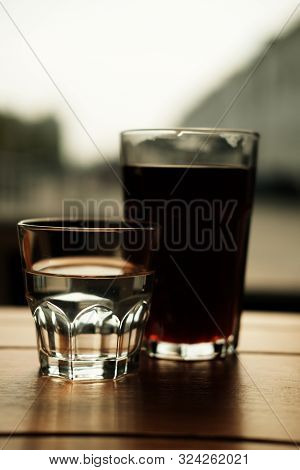 Alternative Coffee And A Glass Of Water Stand On A Wooden Table. Dark Background. Close-up