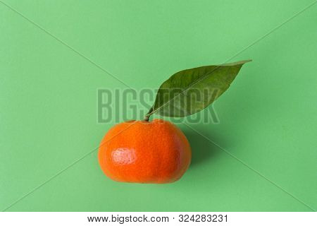 One Ripe Raw Tangerine On Stem With Leaf On Chartreuse Green Background. Vitamins Citrus Fruits Deto
