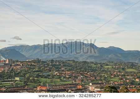 A Beautiful European City At The Foot Of A Mountain Against A Blue Sky