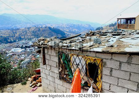 An Old Brick House With A Broken Window And Roof Filled With Garbage Next To A Proper House