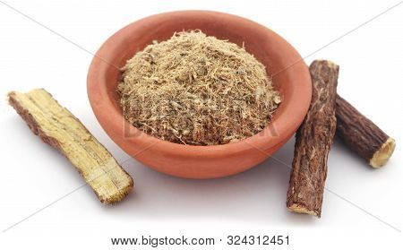 Liquorice Stick And Ground In A Small Bowl Over White Background