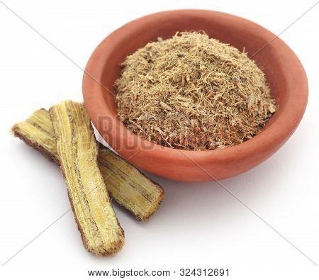 Liquorice Stick And Ground Powder In A Bowl Over White Background