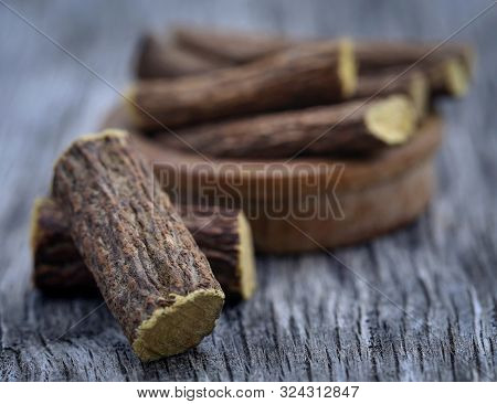 Liquorice Stick In Wooden Bowl On Textured Surface