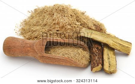Liquorice Stick And Ground In A Wooden Scoop Over White Ackground