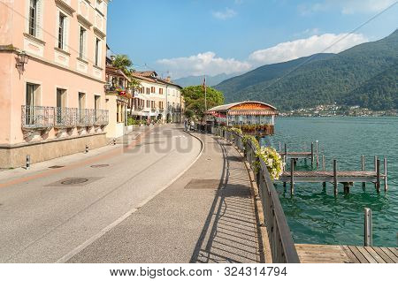View Of Picturesque Village Morcote With Outdoor Bars And Gift Shops On The Shore Of Lake Lugano In