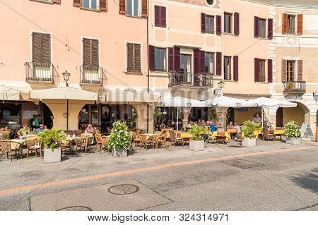 View Of Picturesque Village Morcote With Outdoor Bars And Gift Shops On The Shore Of Lake Lugano In