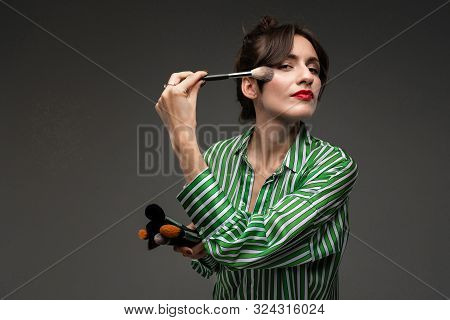 Portrait Of Young Woman Putting On Makeup On Cheeks In Green And White Striped Blouse With Makeup Br