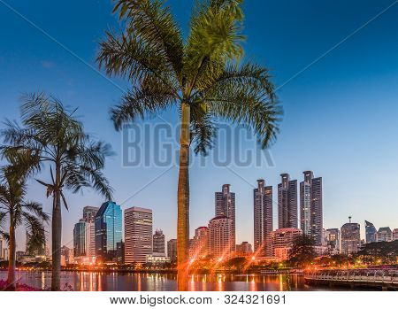 Lake In City Park Under Skyscrapers At Twilight. Benjakiti Park In Bangkok, Thailand