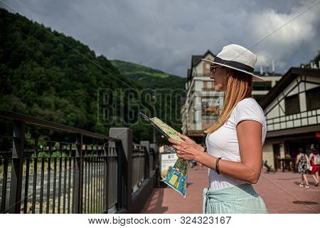 Tourist Girl In Glasses White Hat Holding A Map Looking Forward