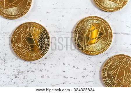 Top Down View, Golden Commemorative Eos - Eosio Cryptocurrency - Coins Scattered On White Stone Boar